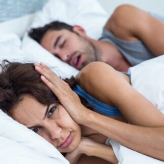 A woman laying in bed next to a man who is sleeping.